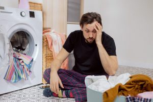 guy-sits-laundry-room-floor-with-washing-machine